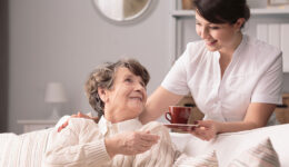 A Hospice Caregiver Handing a Mug to a Senior Woman Sitting on a Couch Benefits of Non-profit Hospice